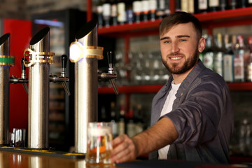Bartender with glass of beer in bar