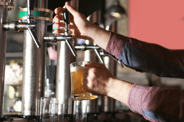 Fototapeta na wymiar Bartender pouring beer into glass in bar