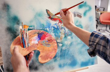Fototapeta Male artist painting on canvas in workshop obraz