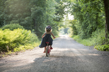 Little Girl Racing down road alone on bicycle