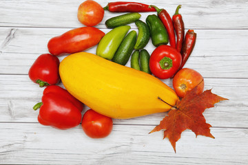 Vegetables and autumn leaves on bright wooden table.