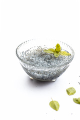 Soaked sweet basil or tukhmaria or falooda seeds or sabja seeds in a bowl with raw sweet basil seed isolated on white with a mint leaf.