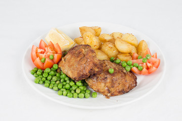 Fried Beef Steak Served With Fried Potatoes, Tomatoes, Peas And Slices Of Lemon On White Plate