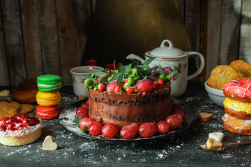 The cake on the black table surrounded by sweets
