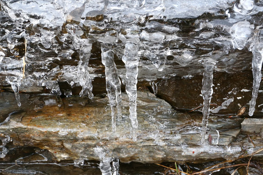 The thawing icicles with the falling water drop in the mountains