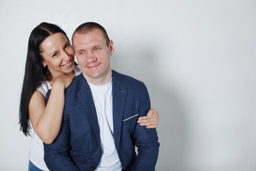 Picture of happy young loving couple standing over grey wall.