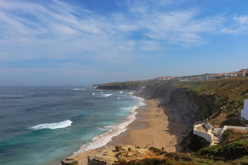 Fototapeta premium Amazing sandy beach in a summer day, with blue waves. Surf spot in Ericeira Portugal