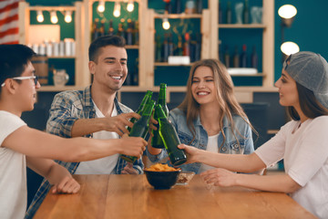 Group of cheerful friends drinking beer in bar