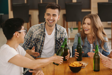 Group of cheerful friends drinking beer in bar