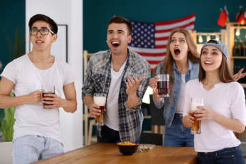 Friends with beer emotionally watching sports in bar