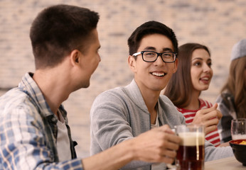Group of cheerful friends drinking beer in bar
