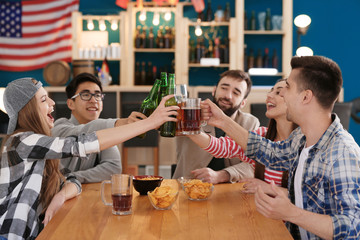 Group of cheerful friends drinking beer in bar
