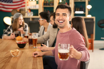 Young man with friends drinking beer in bar