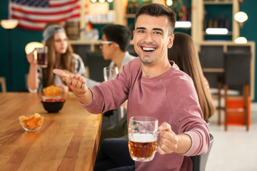 Young man with friends drinking beer in bar