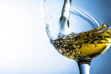 Naklejka na ściany i meble White wine splash on grey background, stream of white wine pouring into a glass. Bright view photo.