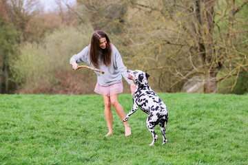 young woman plays with Dalmatian dog outdoors