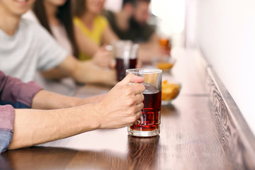 Young man with friends drinking beer in bar