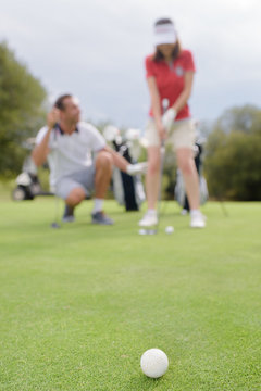 Blurred image of golfing couple, ball in foreground