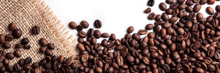 Panoramic background of roasted coffee beans on a white background with a jute sack