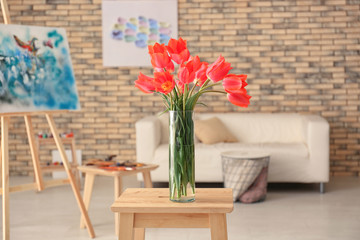 Vase with beautiful tulips on wooden stool indoors