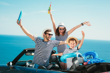 Happy family travel by car to the sea. People having fun in cabriolet. Summer vacation concept