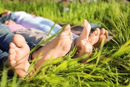 Barefoot family lying on grass in park