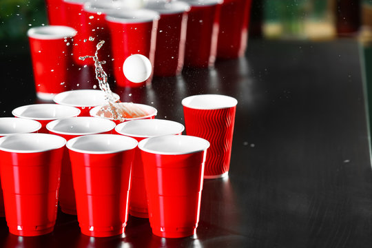 Cups and plastic ball for beer pong game on table