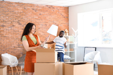 Interracial couple packing carton boxes in room. Moving into new house