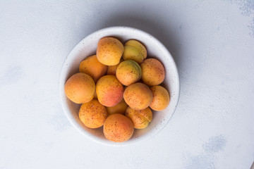 Summer concept. Large beautiful ripe apricots in a ceramic bowl on a white concrete background. Design Copy Space Top View Flat Lay  Close-up.