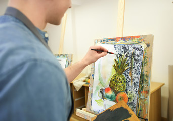 Young art student painting in workshop