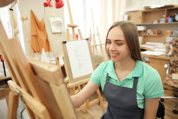 Young female art student painting in workshop
