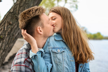 Fototapeta premium Happy young couple kissing near river on spring day
