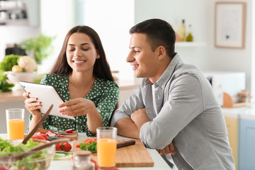 Friends with tablet PC reading recipes in kitchen