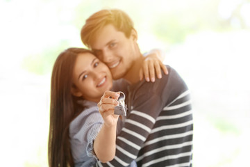 Young happy couple with key of their new house indoors