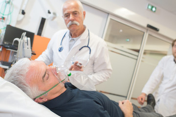 Fototapeta na wymiar doctor applying oxygen mask on senior patient