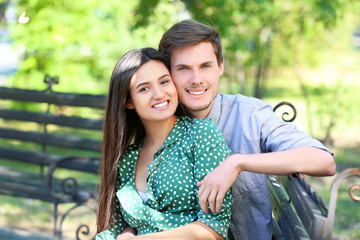Fototapeta premium Young couple resting on bench in green park