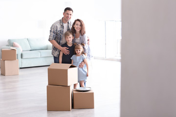 Happy family with cardboard boxes indoors. Moving into new house