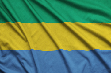 Gabon flag  is depicted on a sports cloth fabric with many folds. Sport team banner