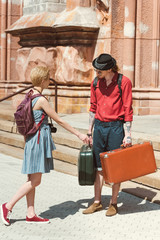 couple of travelers with backpacks and vintage suitcases in city