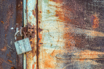 closed old rusty metal door with padlock