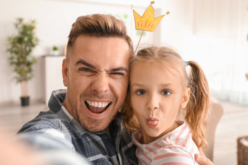 Happy father and daughter taking funny selfie at home