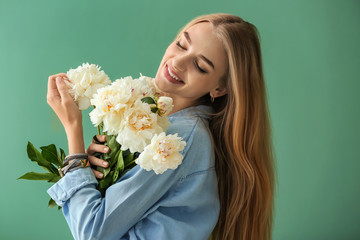 Attractive young woman with beautiful flowers on color background