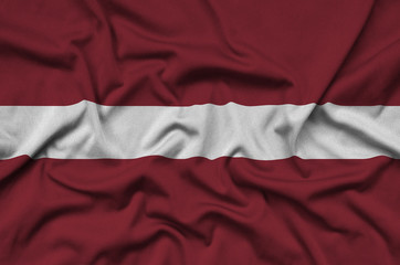 Latvia flag  is depicted on a sports cloth fabric with many folds. Sport team banner