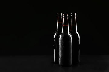 Glass bottles of cold beer on dark background