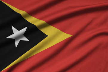 Timor Leste flag  is depicted on a sports cloth fabric with many folds. Sport team banner