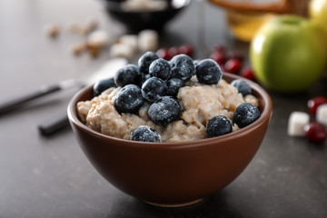 Tasty oatmeal with berries in bowl on table