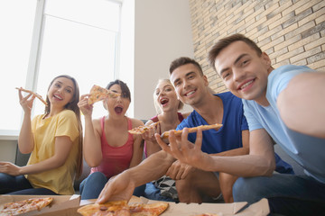 Young people taking selfie with delicious pizza at home party