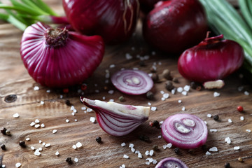 Fresh purple onion with spices on wooden background