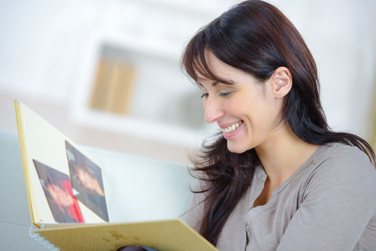 woman looking at photo album in her apartment