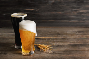 Glasses with cold beer and spikelets on wooden table